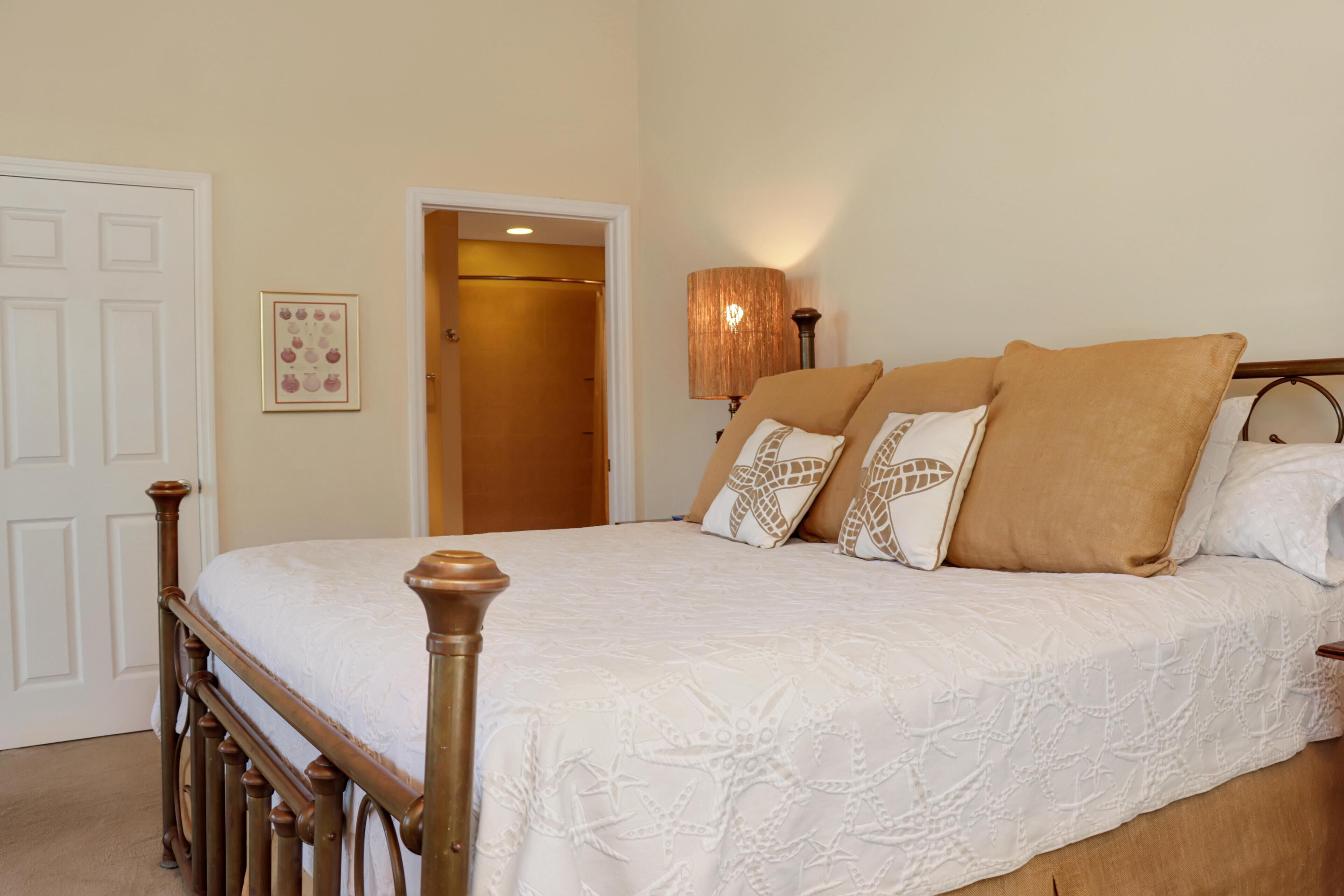 A bedroom with a wooden bed frame, a white bedspread, and a lamp on the nightstand.