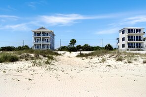 Ein strandnahes Anwesen mit einem zweigeschossigen Gebäude, das Balkone und eine flache Dachterrasse besitzt.