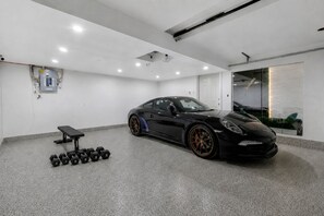 Une salle de sport moderne avec une voiture de sport noire, un banc et des haltères.