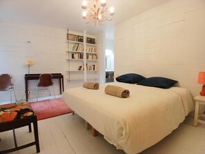 Ein Schlafzimmer mit Bett, Schreibtisch, Stuhl, Bücherregal und einer Deckenleuchte.