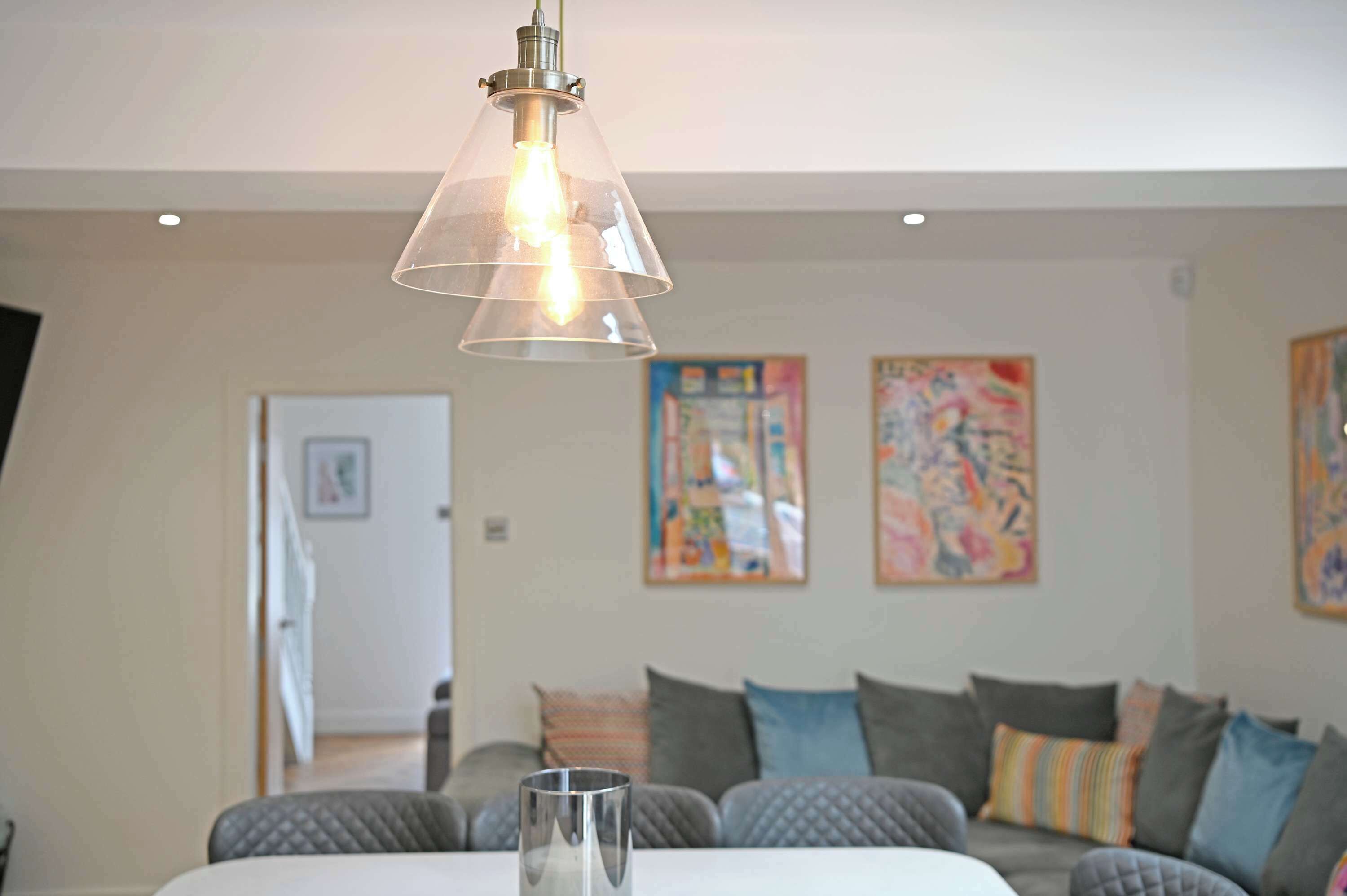 A living room with a clear glass pendant light, a sofa with cushions, and abstract art on the walls.