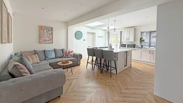 A modern living room with a grey sofa, a small round coffee table, and a herringbone wooden floor. - Stylish Apartment w/ Parking Near York City Centre (York)