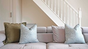 A sofa with three pillows, a white staircase, and a door in a room. - Stylish Apartment w/ Parking Near York City Centre (York)