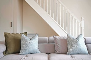 A sofa with three pillows, a white staircase, and a door in a room. - The Green - Stylish Home Sleeps 6 with Parking (York)