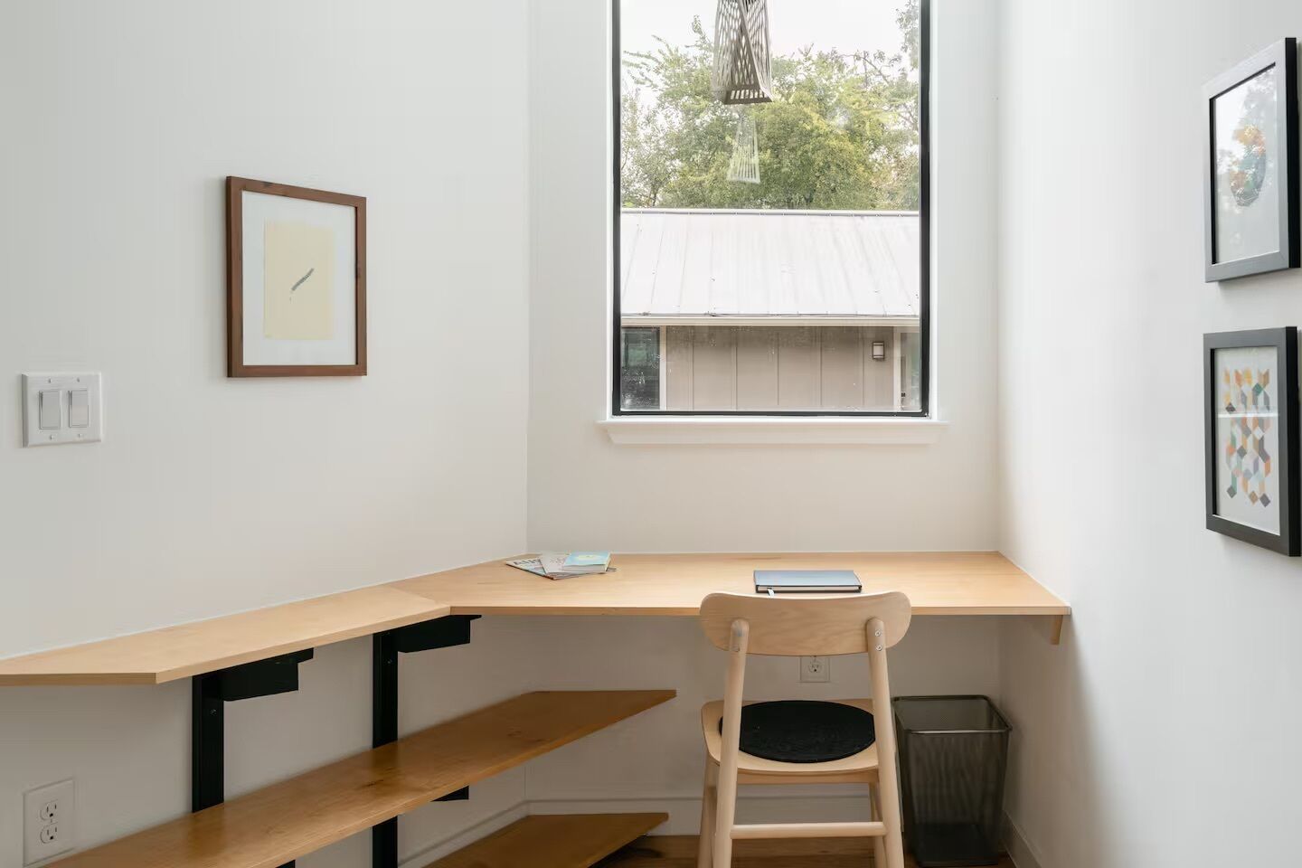 A room with a desk, chair, and a window with a view of a building.