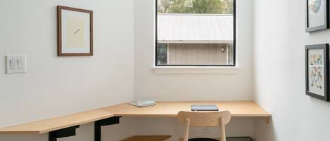 A room with a desk, chair, and a window with a view of a building.