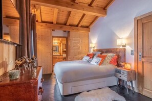 Ein Schlafzimmer mit einem großen Bett, einem Holzkopfstück, Nachttischlampen, einem Koffer und einer rustikalen Einrichtung.