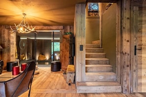 A rustic interior with a wooden staircase, a dining area with a chandelier, and a view through a glass door. - Chalet, 2nd floor, terrace, fireplace or stove, tv, 350m², Combloux (Demi-Quartier)