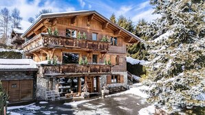 A wooden chalet with a balcony, stone foundation, and a snow-covered landscape. - Chalet, 2nd floor, terrace, fireplace or stove, tv, 350m², Combloux (Demi-Quartier)