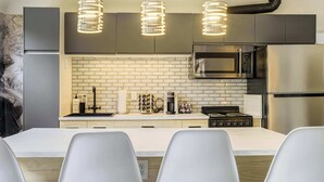 A modern kitchen with a white countertop, stainless steel appliances, and pendant lighting.