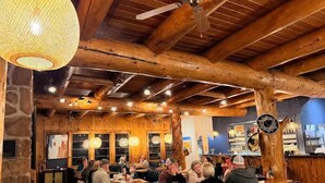 A rustic interior with wooden beams, stone walls, and a bar area.