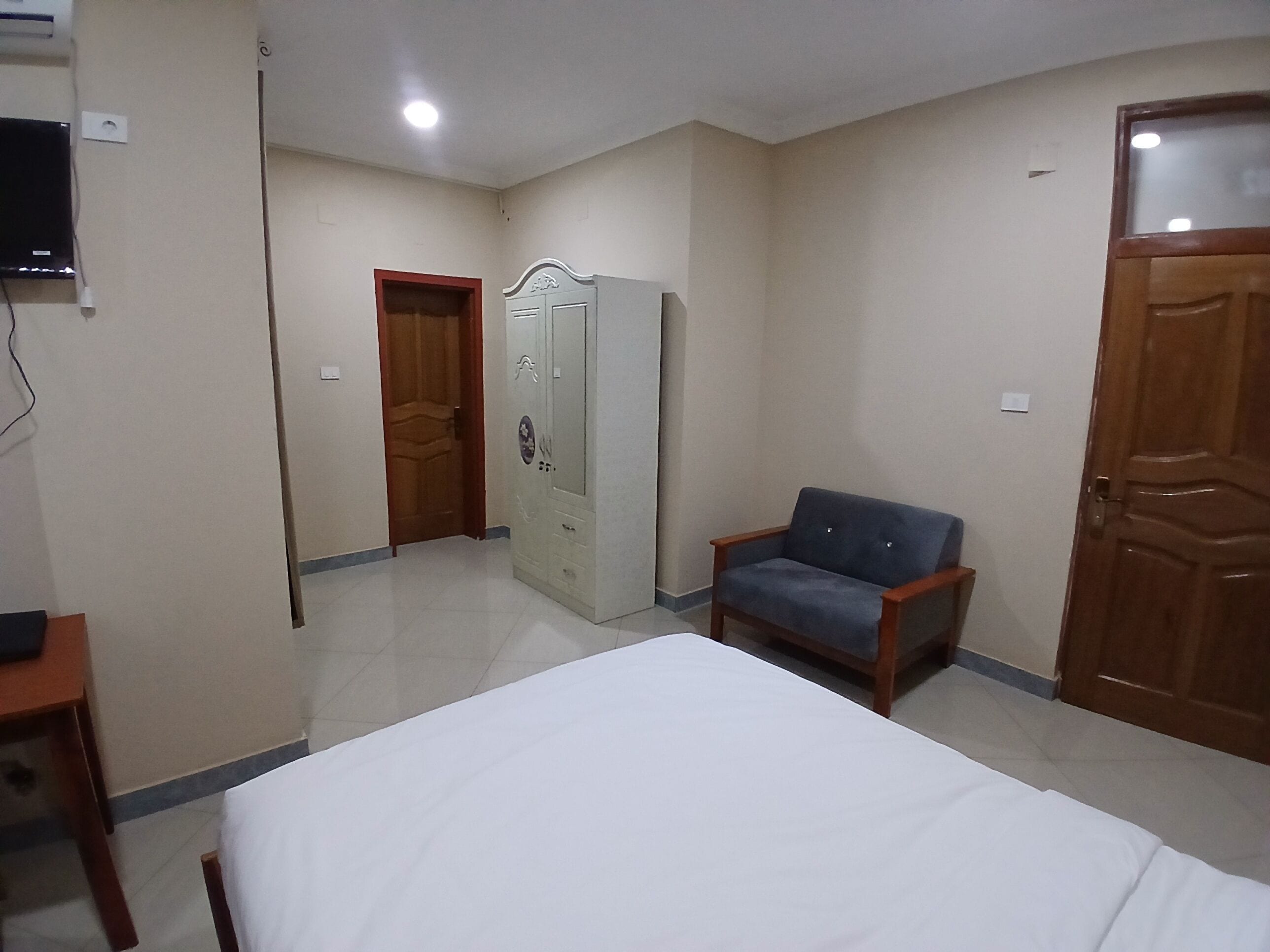A bedroom with a bed, a wardrobe, a chair, and a television.