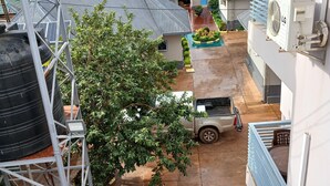 Zona residencial amb un pati pavimentat, un vehicle estacionat i un dipòsit d'aigua sobre una estructura metàl·lica.