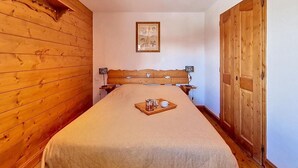Una camera da letto con testiera in legno, un quadro appeso al muro e un vassoio con una tazza e un bicchiere sul letto.