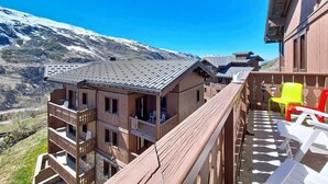 Un edificio in legno con balconi, vista sulle montagne innevate e posti a sedere all'aperto.