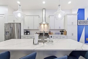 A modern kitchen with a central island, stainless steel appliances, and pendant lighting. - Victory Lane Villa | Game Room - Hot Tub - Firepit (Indianapolis)