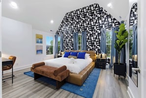 A modern bedroom with a large bed, a desk, and a view of the outdoors. - Victory Lane Villa | Game Room - Hot Tub - Firepit (Indianapolis)
