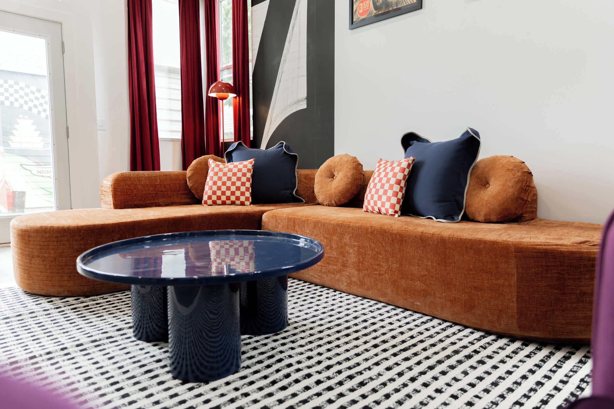 Ein modernes Wohnzimmer mit einer Eckcouch, einem runden Couchtisch und gemusterten Teppichen.