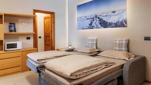 Ein Schlafzimmer mit einem Bett, einer Mikrowelle, einem Regal mit einem Buch und einem Bild an der Wand.