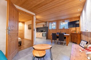 A wooden interior with a dining area, kitchen, and a TV mounted on the wall. - Ground floor, hammam, parking, 40m², Les Gets (Les Gets)