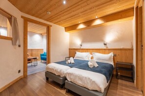 A bedroom with two beds, wooden ceiling, and a desk with a chair in the adjacent room. - Ground floor, hammam, parking, 40m², Les Gets (Les Gets)