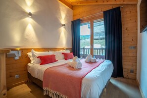 A wooden room with a bed, a window with curtains, and a view of a balcony. - 2nd floor, hammam, balcony, parking, 95m², Les Gets (Les Gets)
