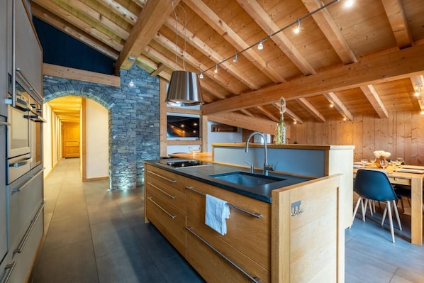 A modern kitchen with a stone archway, wooden beams, and a dining area with a table and chairs. - 2nd floor, hammam, balcony, parking, 95m², Les Gets (Les Gets)