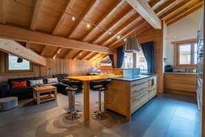 A wooden interior with a kitchen island, bar stools, a sofa, and a dining table. - 2nd floor, hammam, balcony, parking, 95m², Les Gets (Les Gets)