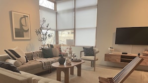 A living room with a sofa, armchair, coffee table, and a TV.