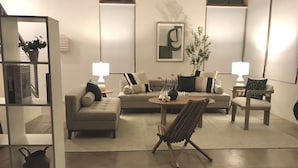 A modern living room with a sofa, armchairs, a coffee table, and a bookshelf.