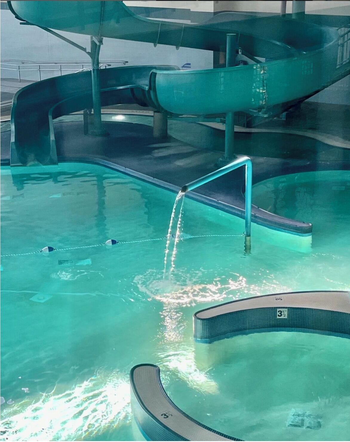 Una piscina con tobogán y trampolín.