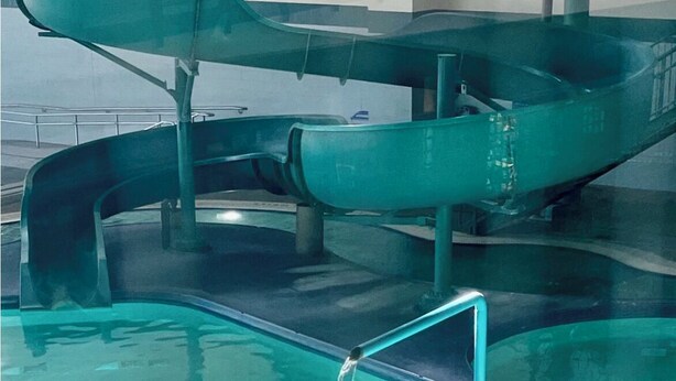 A swimming pool with a water slide and a diving board.