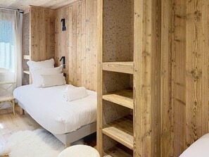 Ein Schlafzimmer mit einem Bett, einem Sessel und Holzböschern.