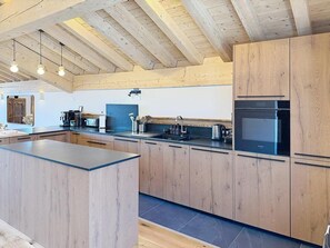 Eine moderne Küche mit Holzausstattung, einer Kochinsel und integrierten Geräten.