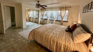 A bedroom with a large bed, a ceiling fan, a window with curtains, and a door leading to another room. - Cozy Spacious Quiant 2-bed 2-bath apartment. (Wilmington)