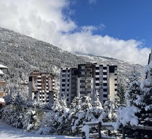A modern building with multiple floors, surrounded by snow-covered trees and a mountainous backdrop. - 150m from ski slopes, 2nd floor, balcony, tv, 30m², Serre Chevalier (La Salle-les-Alpes)