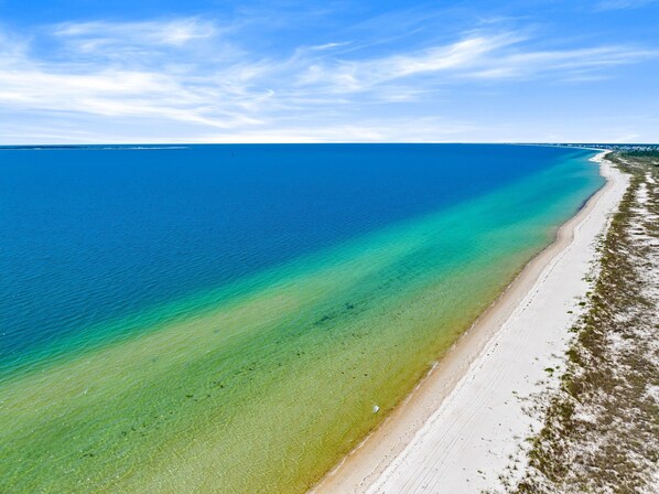 Ein Strand mit klarem Wasser, einem Sandufer und weiter Ferne.