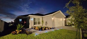 A modern two-story house with a garage, well-maintained lawn, and outdoor lighting. - Encanto At Auburndale (Auburndale)