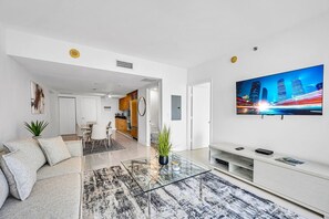 Ein stilvolles Wohnzimmer mit einer Couch, einem Couchtisch und einem Fernseher, der eine Stadtansicht zeigt.