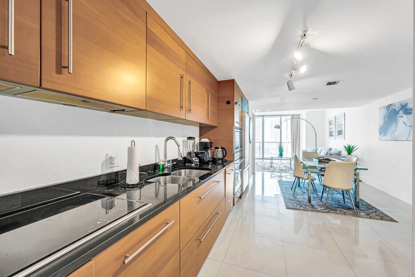 A modern kitchen with wooden cabinets, a black countertop, and stainless steel appliances.