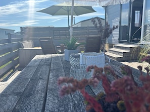 Eine Holzterrasse mit Gartenmöbeln, einem Blumentopf und einem Glaskerzenhalter.