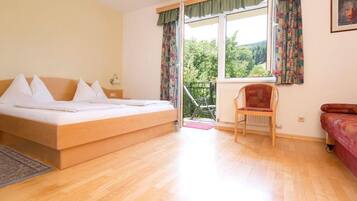Un dormitorio con cama, una silla, un sofá y una ventana con cortinas.