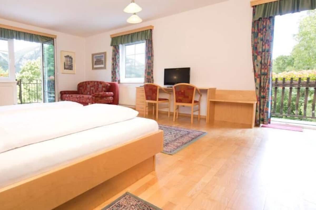 A bedroom with a bed, a desk, a chair, and a TV.