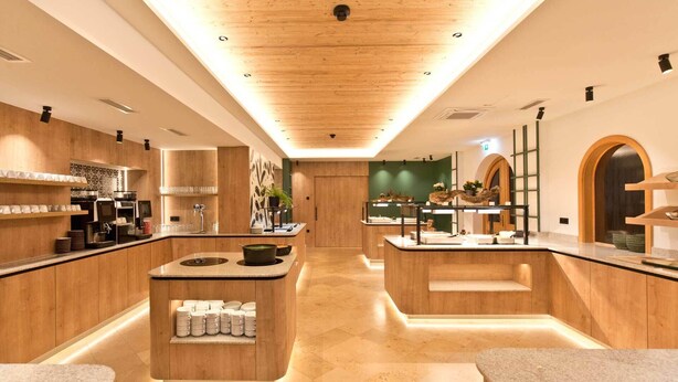 A modern hotel lobby with wooden paneling, a central island with a sink, and a seating area with a counter. - Flackl - Wirt  (Reichenau an der Rax)