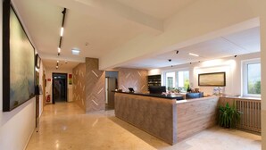 A modern reception area with a wooden reception desk, a fire extinguisher, and a potted plant. - Flackl - Wirt  (Reichenau an der Rax)