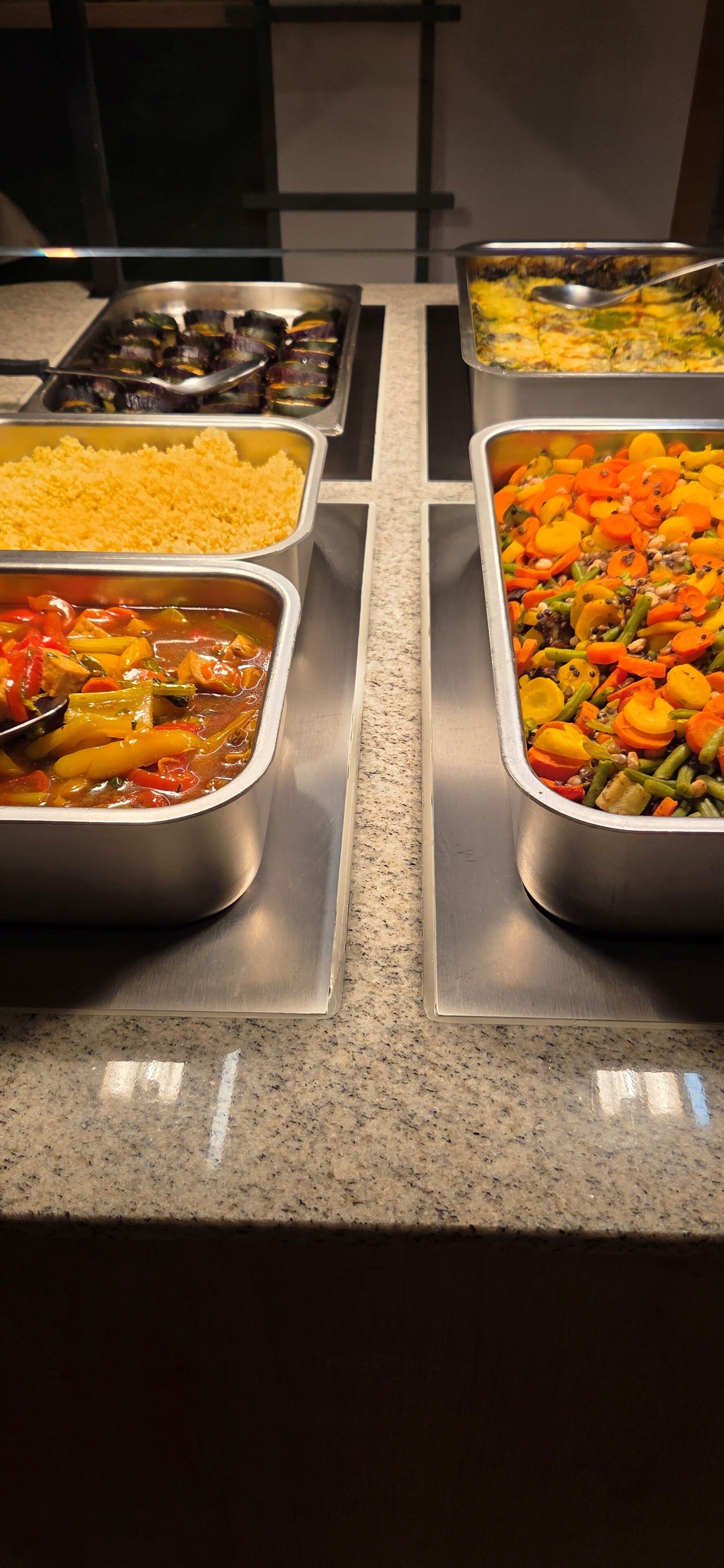 Un buffet proposant divers plats, notamment du riz, des légumes et un plat en gratin.