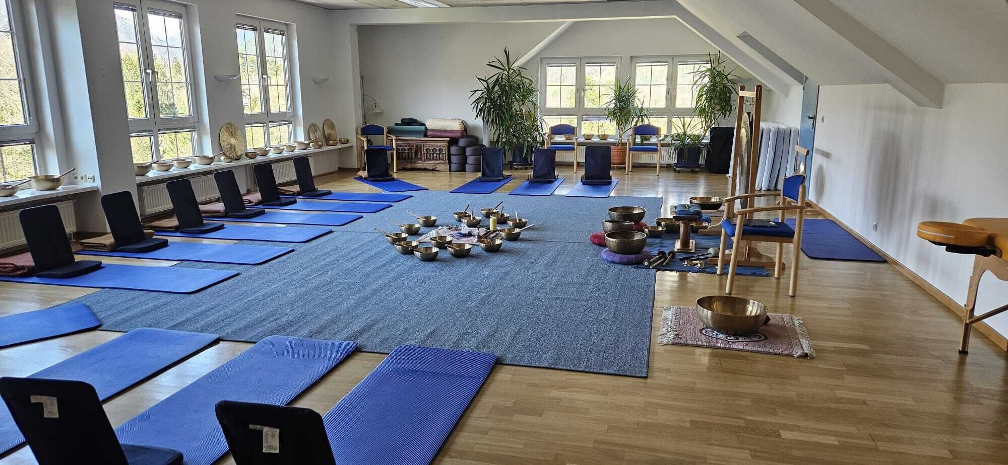 A yoga studio with mats, chairs, and meditation bowls arranged for practice.