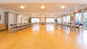 Ein Konferenzraum mit Stuhlreihen, einem langen Tisch und großen Fenstern.