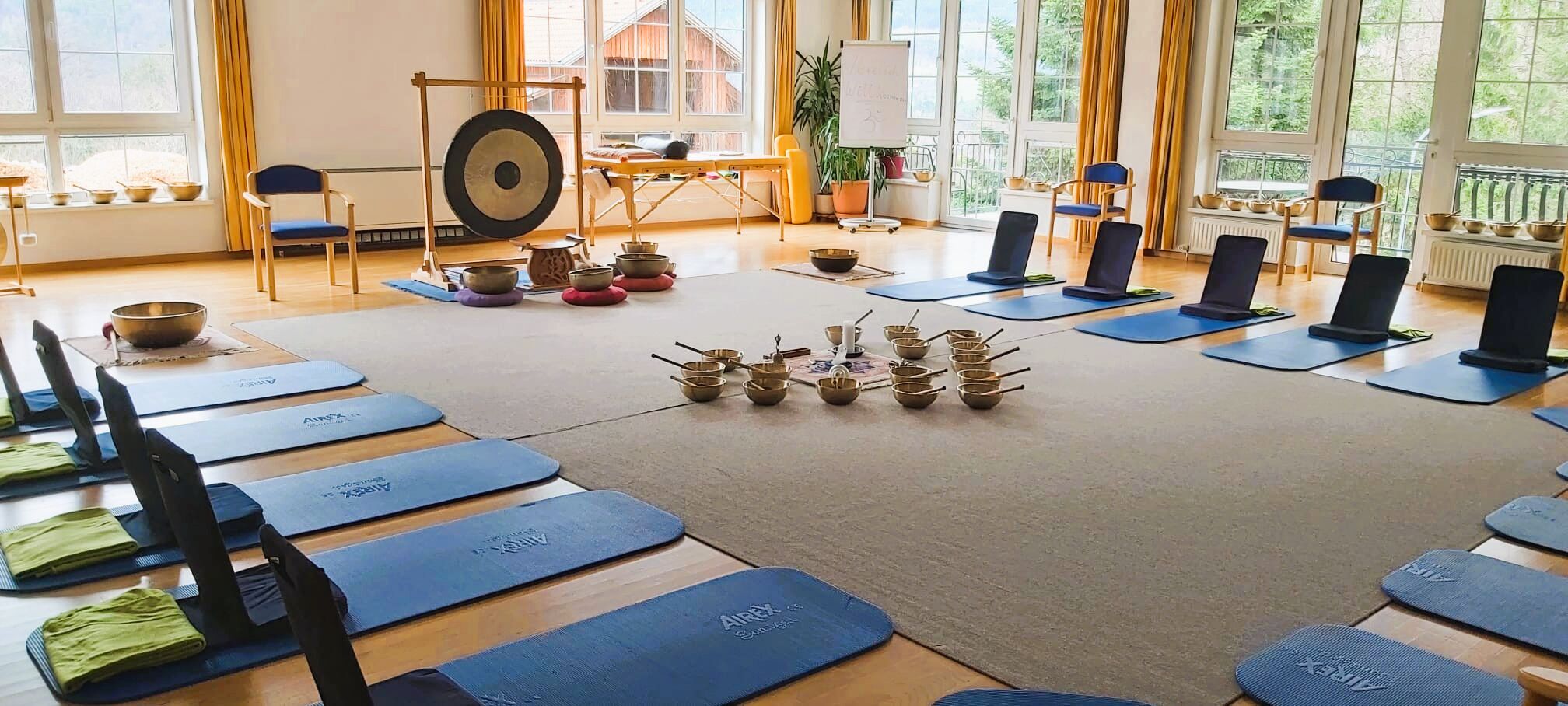 A yoga studio with mats, bowls, and a gong.