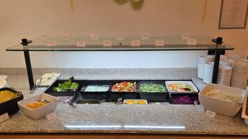 Un mostrador de buffet con diversas opciones de comida, como ensaladas, verduras y un plato al horno.